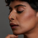 Woman wearing a minimal round 18K gold nose pin shown in side profile highlighting a subtle everyday jewellery look