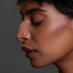 Side profile of a woman wearing a minimal gold nose pin showcasing an elegant everyday look