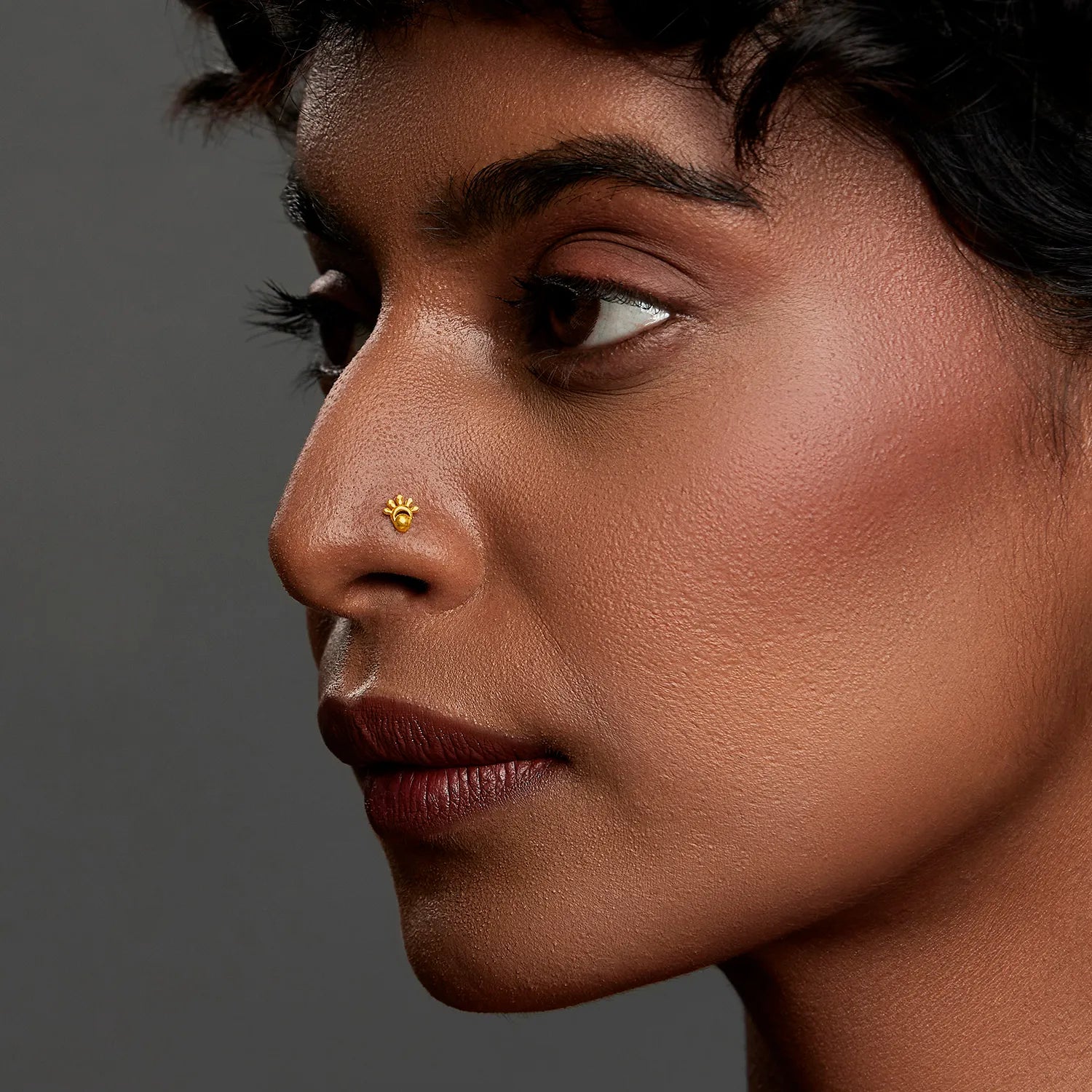 Woman wearing a tiny 18K nose pin gold in side profile highlighting a refined and elegant everyday look