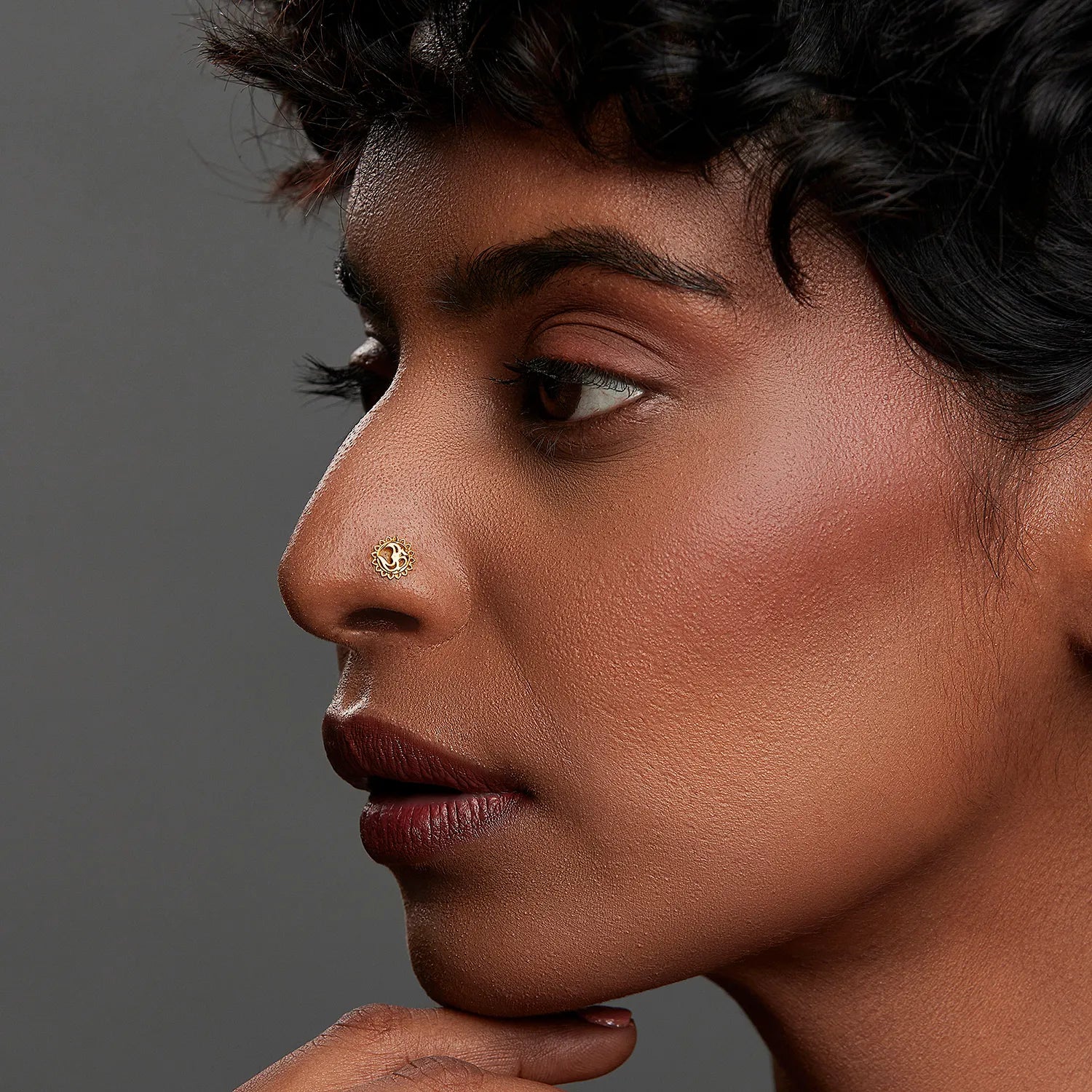 Woman wearing a small 18K nose pin gold showcasing a refined side profile with elegant facial detailing