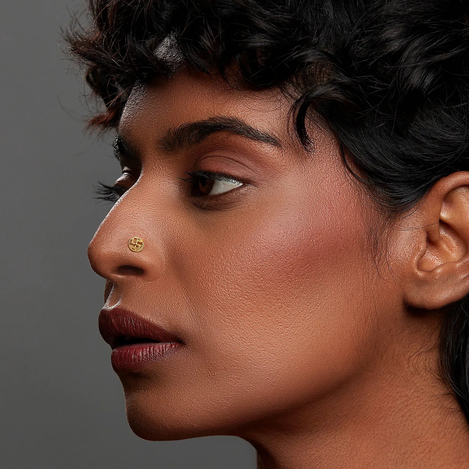 Woman wearing a small 18K nose pin gold showcasing a bold and elegant side profile look