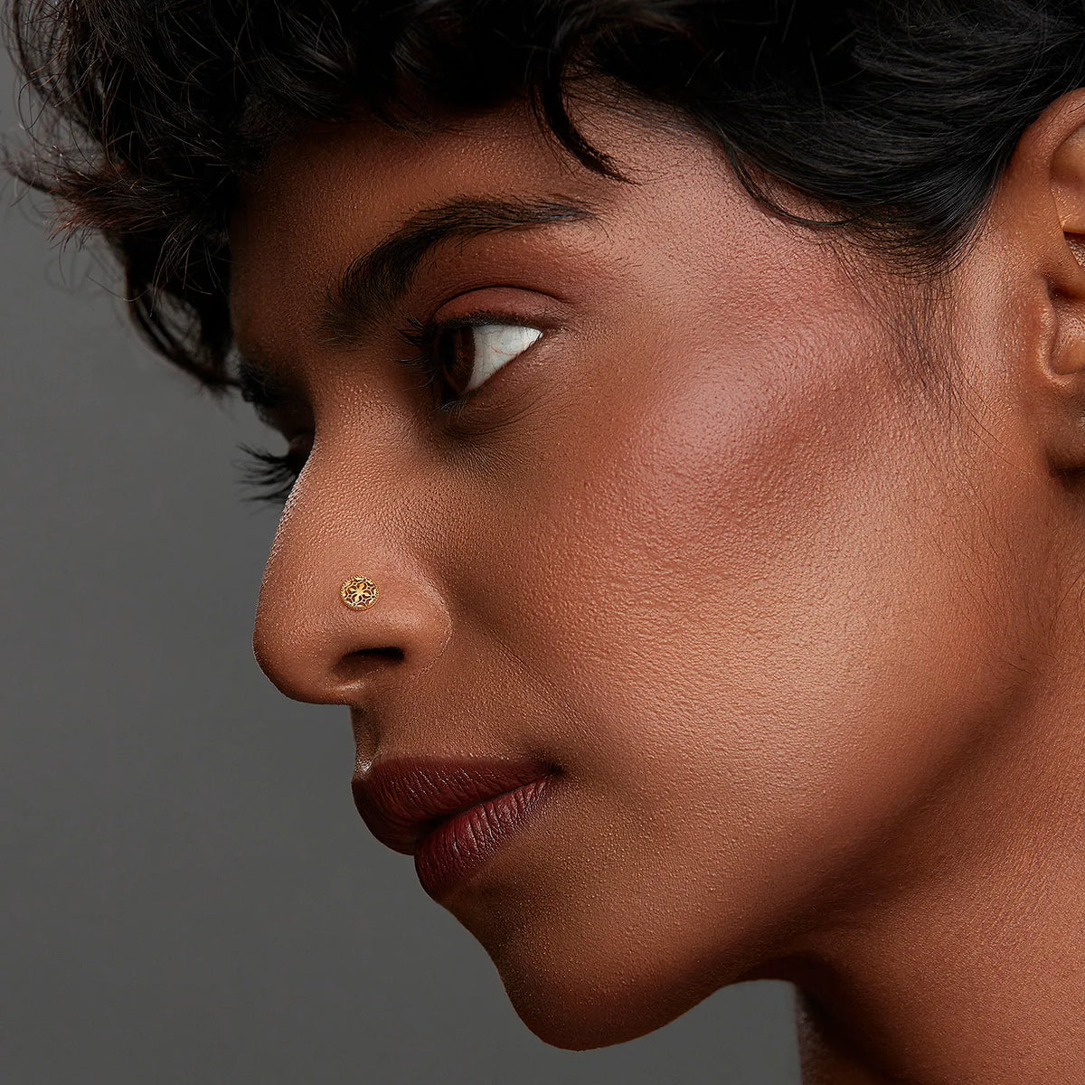 Woman wearing a tiny 18K nose pin gold in side profile showcasing a subtle and elegant everyday look