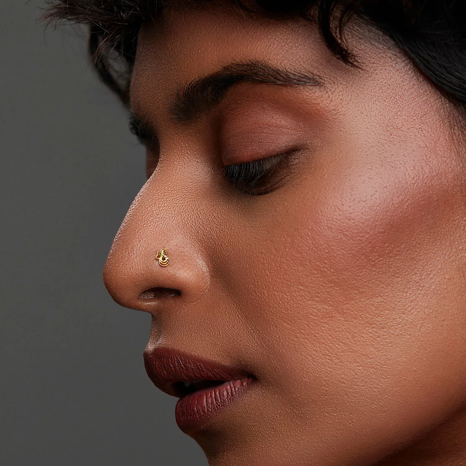 Woman wearing a tiny 18K nose pin gold shown in side profile highlighting a subtle minimalist look and natural elegance