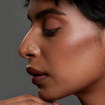 Side profile of a woman wearing a delicate 18K gold nose pin showing an elegant and minimal everyday look