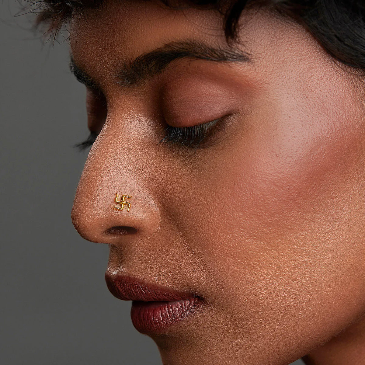 Woman wearing a swastik motif 18K nose pin gold showcasing a traditional yet minimalist ethnic look
