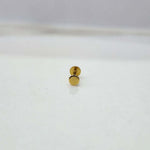 Close-up of tiny round gold nose pin placed on white surface showing clean detailing