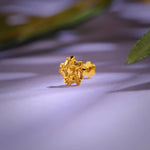 Close up of an intricate floral 18K nose pin gold placed on a soft pastel background highlighting detailed craftsmanship