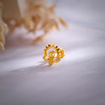 Close up of a floral 18K nose pin gold placed on a soft white surface highlighting intricate craftsmanship and polished finish