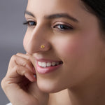 Woman wearing elegant gold nose pin showcasing traditional crescent motif and classic indian look