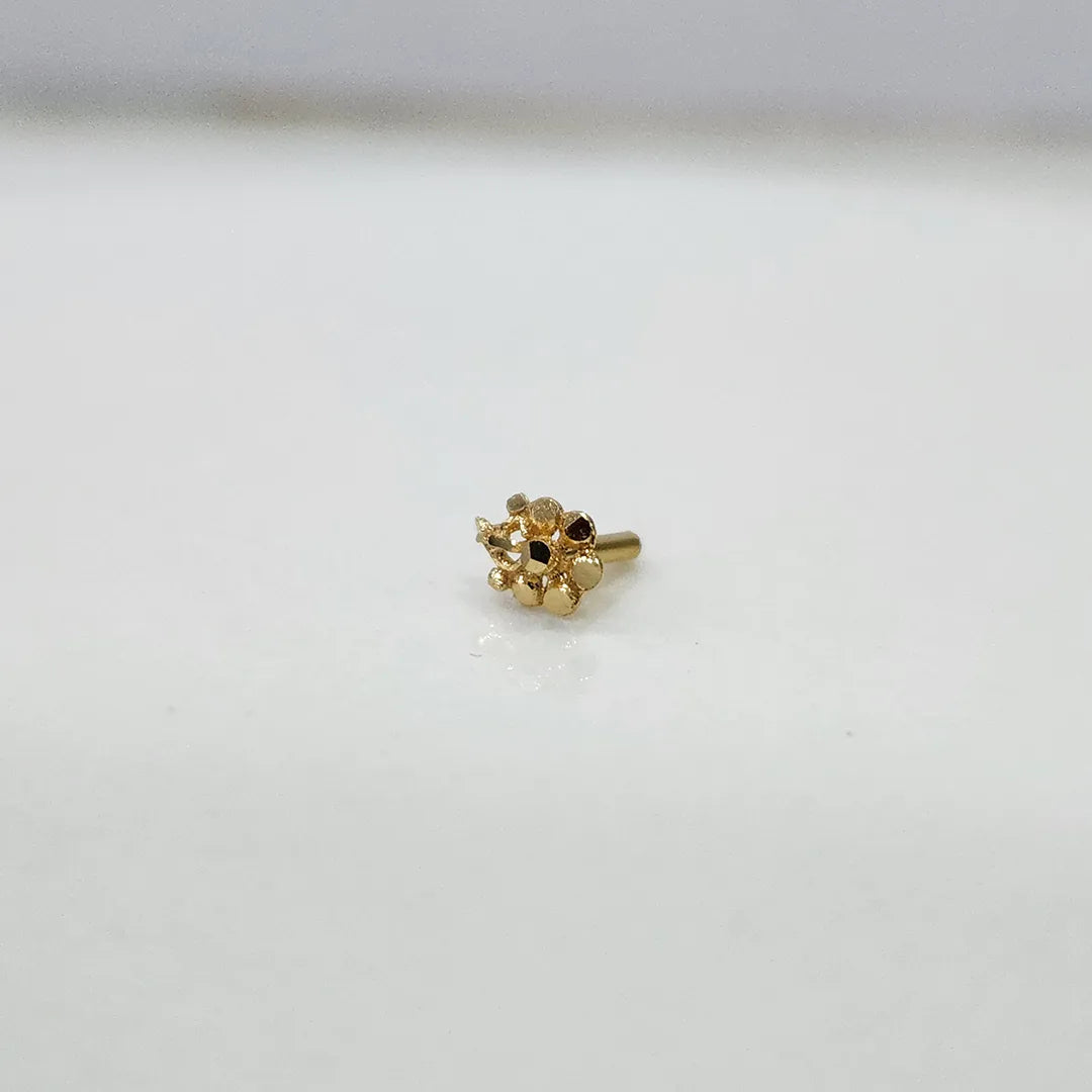 Close up of a small floral 18K nose pin gold placed on a white background showing fine craftsmanship and compact size