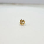 Close up front view of a floral inspired 18K gold nose pin placed on a clean white surface highlighting intricate petal detailing and compact size
