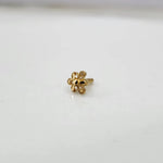 Side angle view of a floral 18K nose pin gold on a white surface showing delicate structure and polished edges