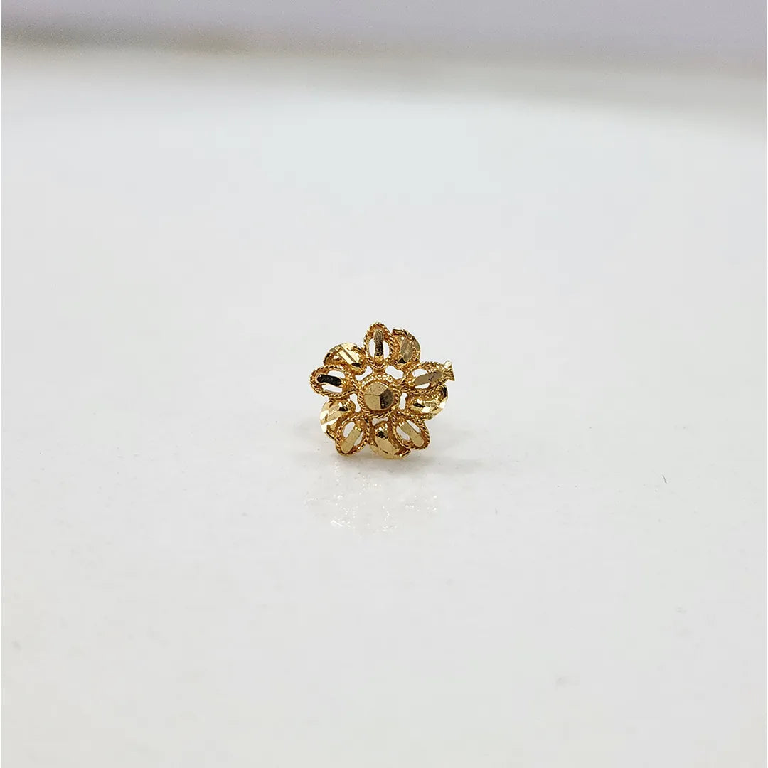 Close-up of the floral 18K gold nose pin on a smooth white surface displaying its polished finish