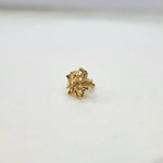 Front view of a small floral 18K gold nose pin on a white background showing its fine petal design