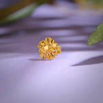 Close-up of a floral 18K gold nose pin placed on a soft purple surface highlighting its intricate handcrafted detailing