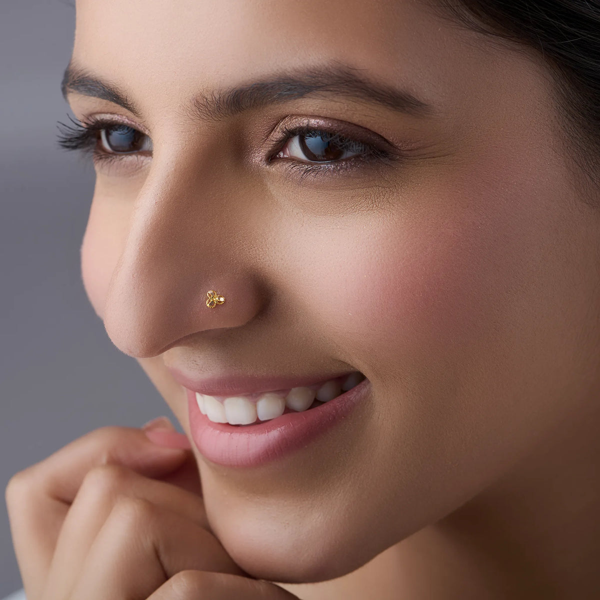 Woman wearing delicate gold nose pin design highlighting three petal floral style and graceful indian look