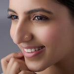 Woman wearing delicate gold nose pin design highlighting three petal floral style and graceful indian look