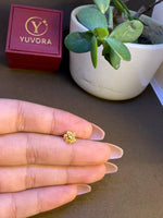 Hand holding a small 18K nose pin gold near a jewellery box showing its tiny wearable size and lightweight design
