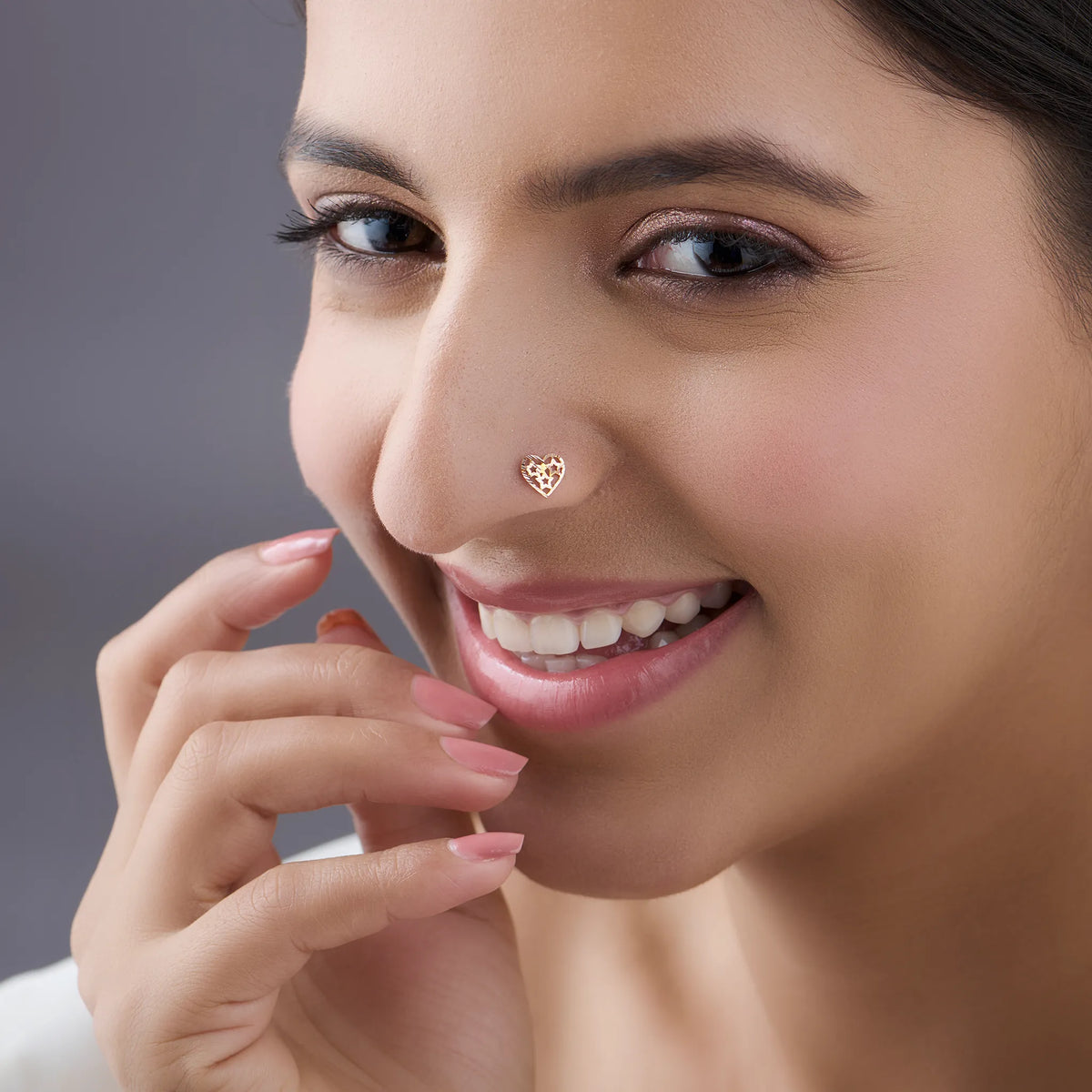 Woman wearing stylish gold nose pin design showcasing heart motif and elegant minimal look