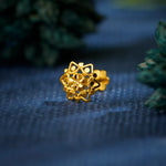 Close up of an intricate floral 18K nose pin gold placed on a textured blue surface highlighting detailed craftsmanship