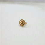 Side view of a tiny 18K nose pin gold on a white surface displaying its compact size and polished finish