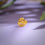 Close-up of an ornate floral 18K nose pin gold placed on a soft pastel surface highlighting its intricate openwork design