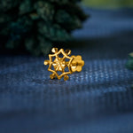 Close up of geometric star inspired 18K gold nose pin placed on textured blue fabric with soft natural accents