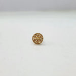 Front angle view of the round floral 18K gold nose pin placed on a white surface emphasizing its compact size