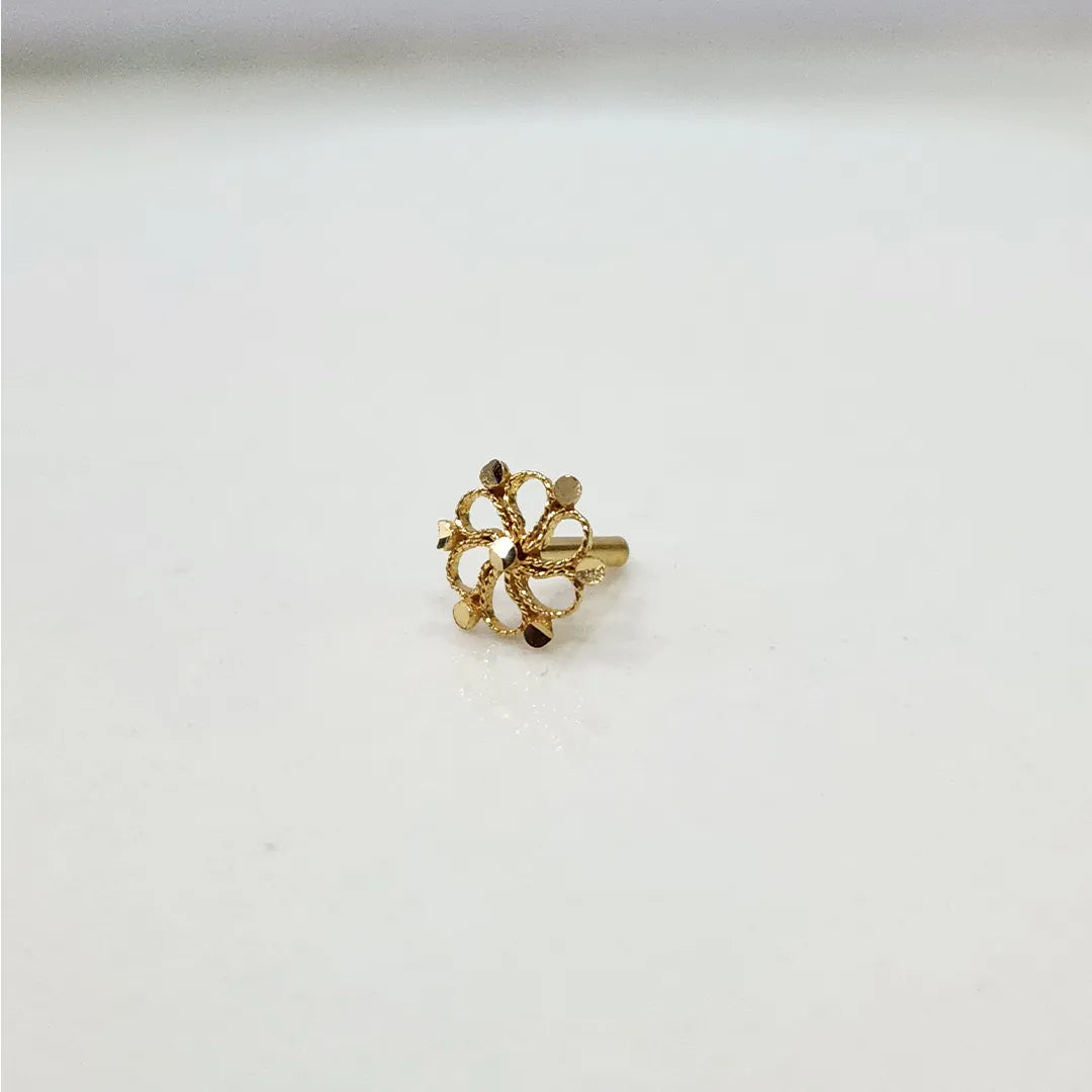 Side view of a tiny floral 18K nose pin gold on a white surface highlighting its compact size and polished finish