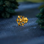 Close up of a floral 18K nose pin gold placed on a textured blue surface highlighting its intricate openwork design