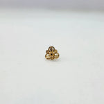 Side view of the 18K gold floral nose pin on a white surface highlighting its polished finish