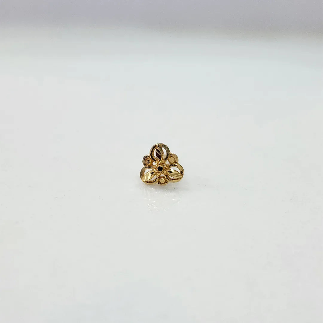 Side view of the 18K gold floral nose pin on a white surface highlighting its polished finish
