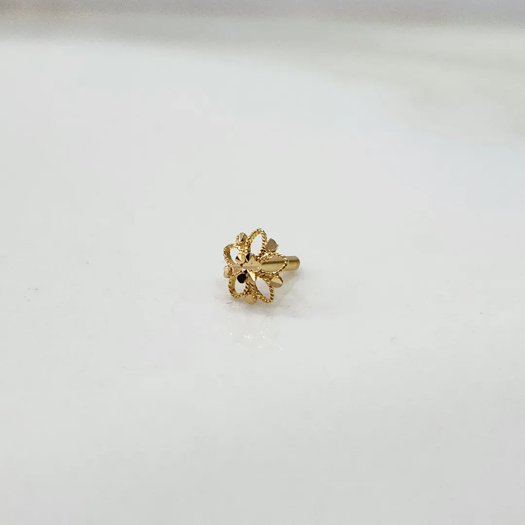 Tiny 18K gold floral nose pin placed on a white surface highlighting its polished shine