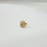 Tiny 18K gold floral nose pin placed on a white surface highlighting its polished shine