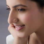 Side profile of a woman wearing a minimal 18K gold floral nose pin showing its subtle and refined appearance