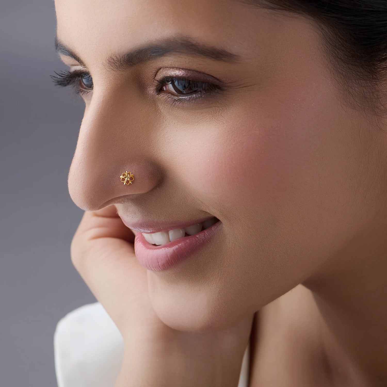 Side profile of a woman wearing a minimal 18K gold floral nose pin showing its subtle and refined appearance