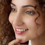 Woman smiling while wearing a delicate 18K gold floral nose pin showcasing an elegant everyday look