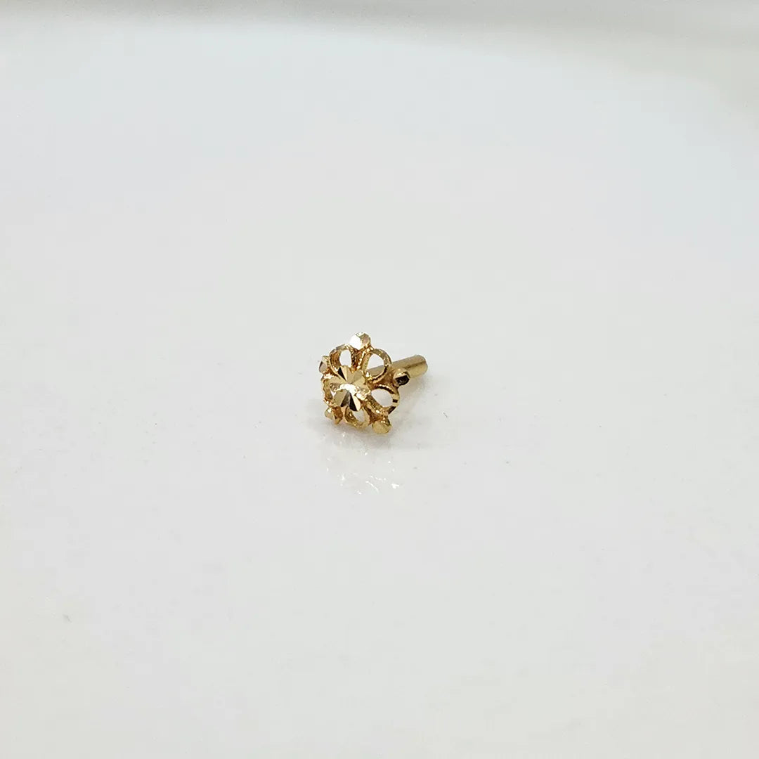 Side view of a tiny 18K gold floral nose pin on a white background showing fine detailing