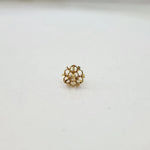 Side view of a delicate 18K gold floral nose pin on a white surface highlighting its polished finish