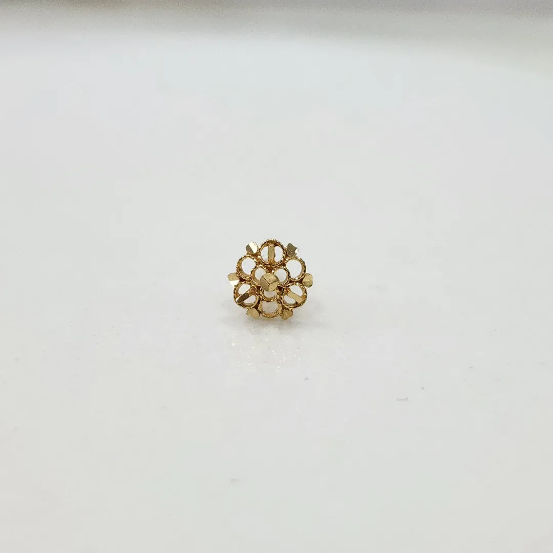 Side view of a delicate 18K gold floral nose pin on a white surface highlighting its polished finish
