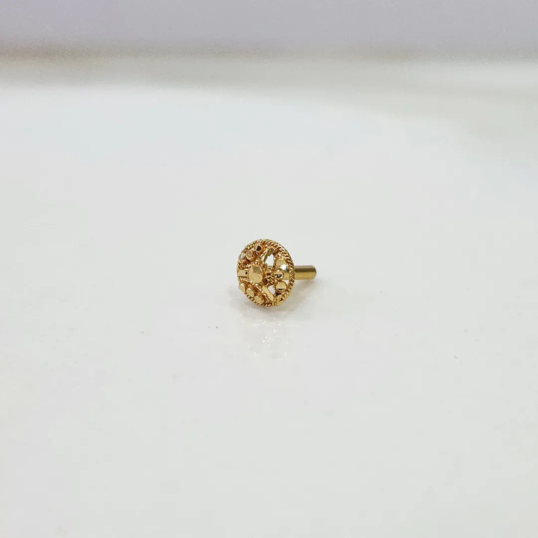 Side view of small 18K floral gold nose pin placed on a white surface displaying its polished finish