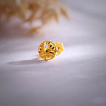 Close-up of an intricate 18K floral gold nose pin placed on a soft surface showcasing its detailed craftsmanship