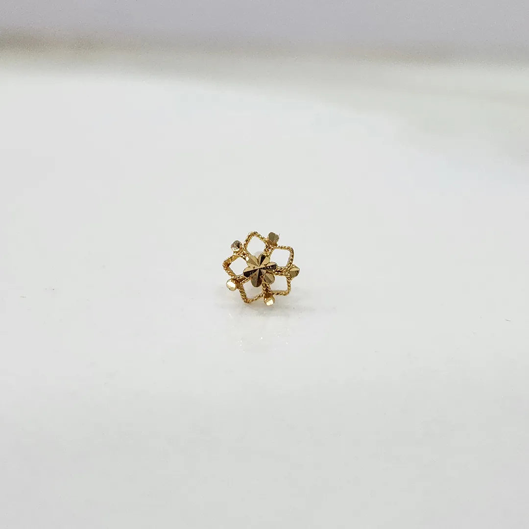 Side view of a delicate 18K gold floral nose pin placed on a white surface displaying its polished finish