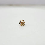 Side angle view of a compact 18K nose pin gold on a white surface showing smooth edges and subtle shine