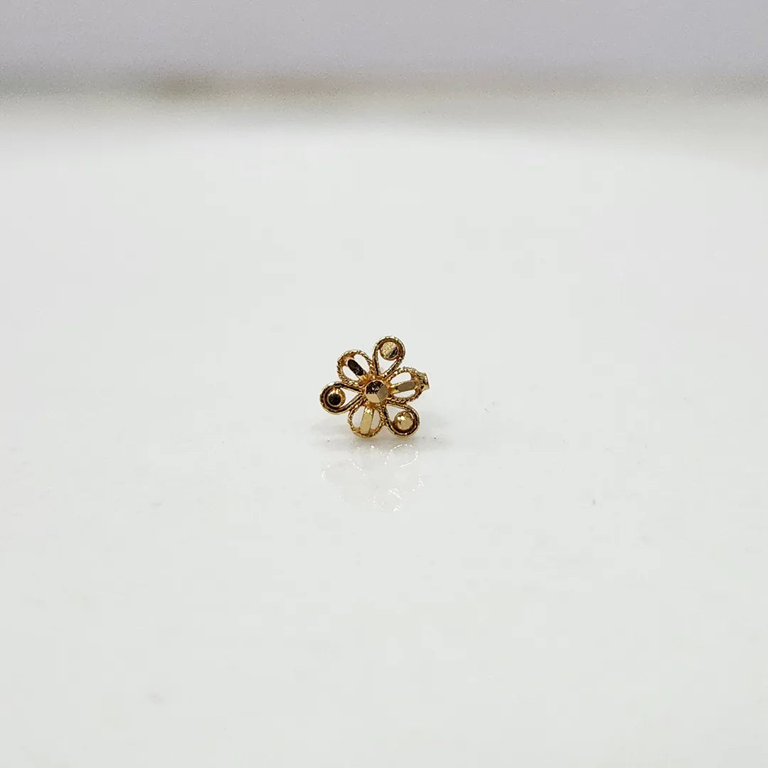 Side angle view of a compact 18K nose pin gold on a white surface showing smooth edges and subtle shine