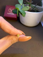 Hand holding a tiny 18K nose pin gold near a jewellery box showing its lightweight feel and small wearable size