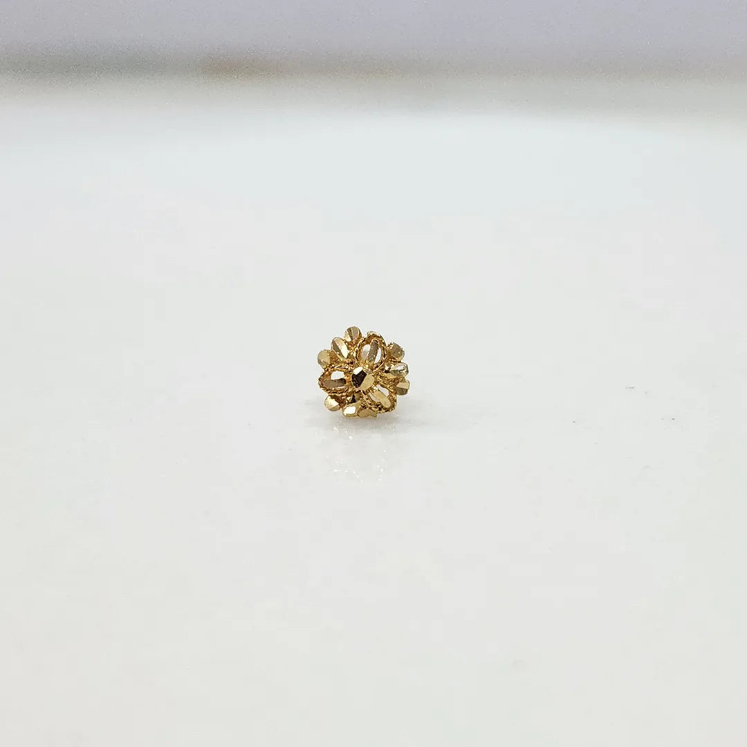 Side view of small 18K floral gold nose pin placed on a white surface displaying its polished finish