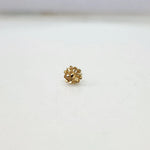 Side view of small 18K floral gold nose pin placed on a white surface displaying its polished finish