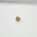 Front view of tiny 18K floral gold nose pin on a white background showing its fine design