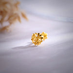 Close-up of an intricate 18K floral gold nose pin placed on a soft surface showcasing its detailed craftsmanship
